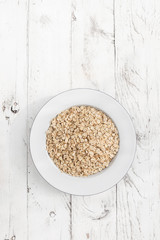 Obraz na płótnie Canvas Oatmeal. Rolled oats flakes on white wooden background
