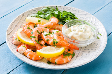 Grilled shrimps, parsley and lemon on blue wooden table

