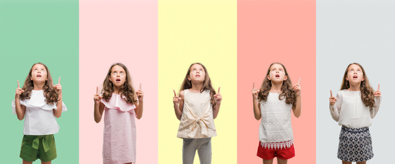 Collage of brunette hispanic girl wearing different outfits amazed and surprised looking up and pointing with fingers and raised arms.