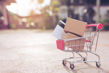 Shopping online concept : Cartons or Paper boxes and credit card in shopping cart on concrete floor. online shopping consumers can shop from home and delivery service. with copy space