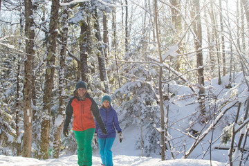 Pair of female friends snowshoeing in forest.