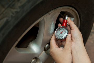 Tire pressure gauge : Hand holding pressure gauge checking air pressure for car tire. Safe driving.