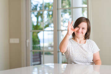 Down syndrome woman at home doing ok sign with fingers, excellent symbol