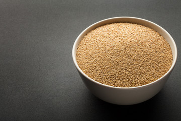 amaranth seeds in ceramic bowl isolated on dark background