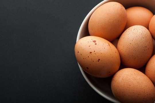 closeup brown eggs in bowl isolated on dark background