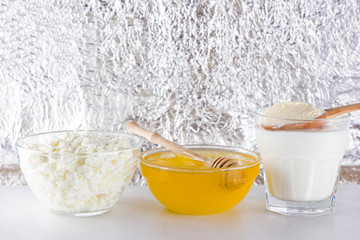 Dairy products and honey with wooden cutlery. Cottage cheese, sour cream, cream on a white background top view. Different natural products for vegan. Healthy food. Copy space
