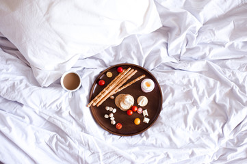 Tasty breakast on wooden tray in hotel room closeup. Top view.