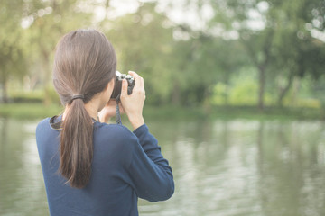 pretty cool young Asian woman with retro film camera or mirrorless camera in modern garden park