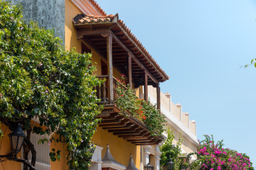 Fototapeta na wymiar Balconies in wooden Cartagena filled with flowers in a vertical garden. Colombia .