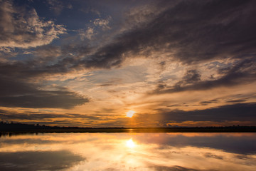 Sunset in the lake. beautiful sunset behind the clouds above the over lake landscape background. dramatic sky with cloud at sunset