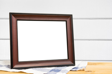 Picture frame put on wooden table in white wood wall room.