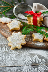 Preparation for new year 2019: pastry biscuits in the form of stars with powdered sugar, decorated  red bow and branches of a Christmas tree. the table with powdered sugar in the form of a snowflake
