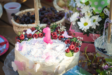 First year birthday cake closeup with cream and berries, selective focus
