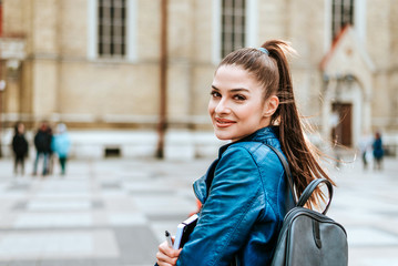 Stylish brunette student at city street looking at camera.