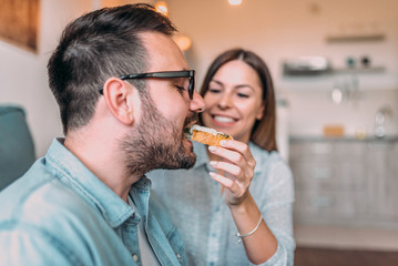 Close-up image of husband eating sandwich from his wife's hand.