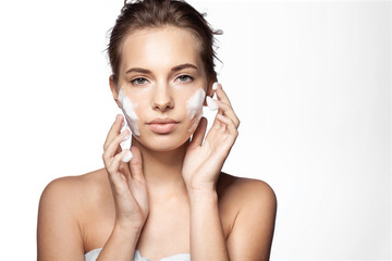 Portrait of young pretty woman applying foaming cleanser on white background. Lovely female with clean fresh perfect skin looking at camera with calmness. Skincare concept. 