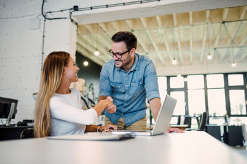Two colleagues handshaking in a modern office.