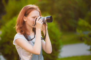 Red-haired girl photographer in the Park