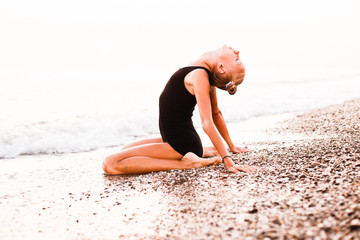 A gymnast in a beautiful pose against the background of the ocean.
