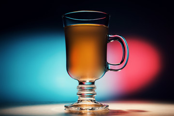 glass mug with a drink on the background of colored glares
