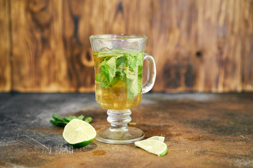 cold tea cocktail with ice and straw on wood board and blue background