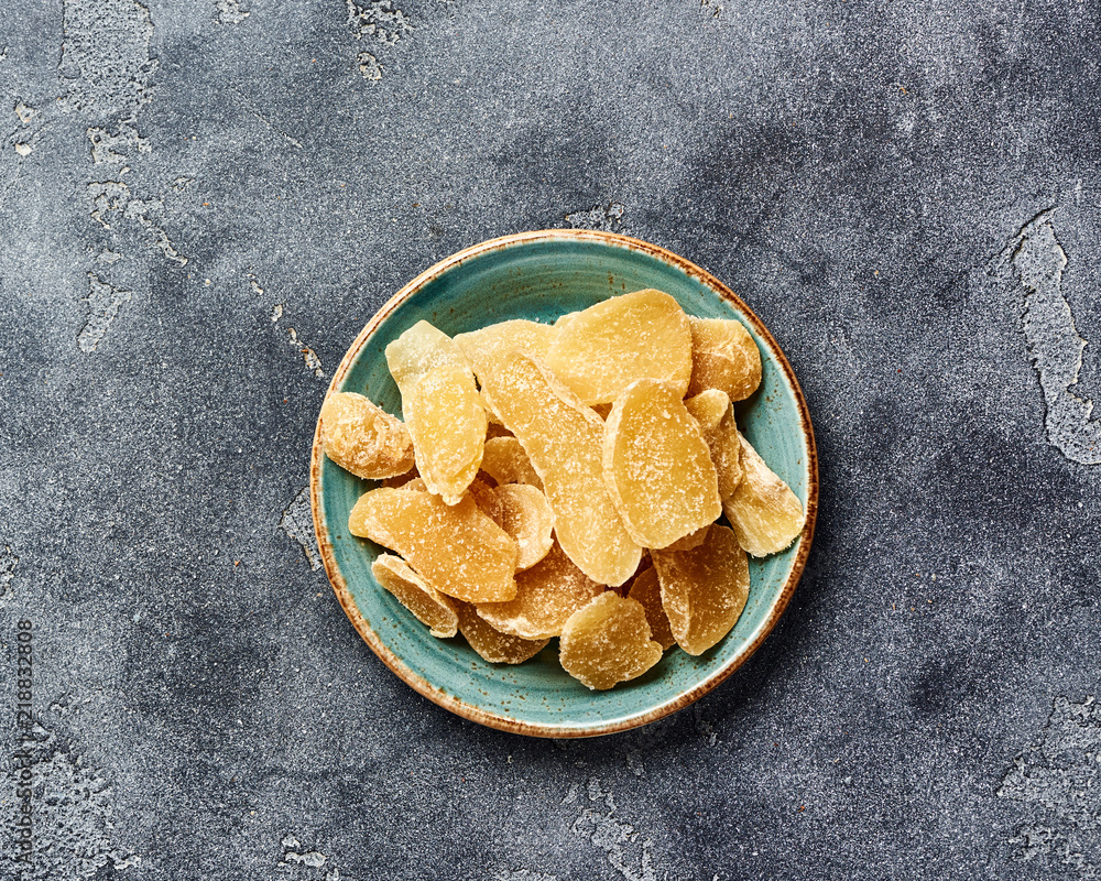 Wall mural Dried sweet ginger with sugar on a gray table. Top view.