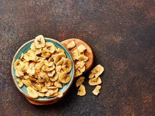 Dried banana slices on brown background. Top view of banana crunchies.