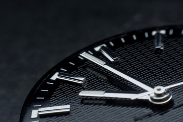 Close up clockwise on black clock face background. Wristwatch in retro style