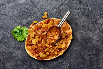Yellow big raisins on black concrete background with copy space. Top view of dried grapes.