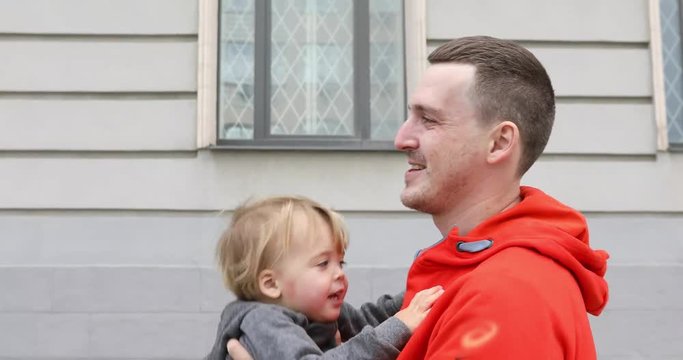Father And Son Cuddling Together on a street. Dady throws laughing baby boy