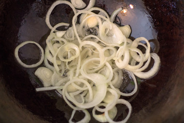 Fry onions for cooking pilaf meat with rice on fire in a cauldron. Recipe