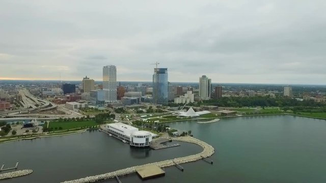 A slow motion aerial drone clip in slow motion shows off the harbor, highways and lakefront skyline of Milwaukee, Wisconsin, as a storm moves over the city at sunset. A perfect establishing shot.