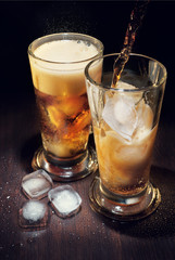 Drink with ice in a glass. Pouring a drink