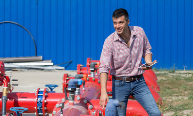 Engineer with tablet beside pipeline