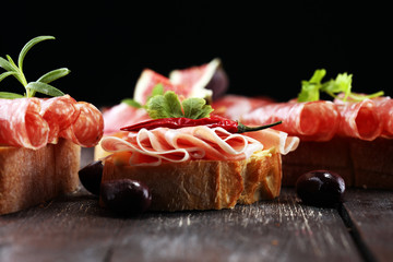 Sandwich with prosciutto or salami or crudo. Antipasti gourmet bruschetta snack.