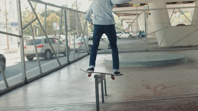 Skater skateboarder man boy doing boardslide trick down the rail in skatepark, close up, 50-50 5-0 five-o slide grind in park on rail