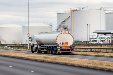 Tanker lorry in motion on the road with oil depot in the background