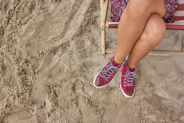 woman wearing red sneakers on a chair on a beach