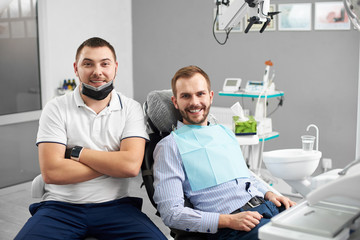 Obraz premium Doctor is sitting next to satisfied patient in dental chair. Modern dentistry with the use of new technologies