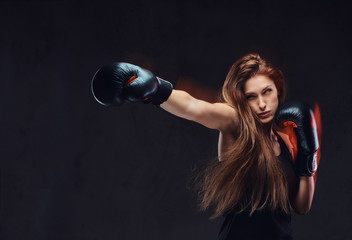 Beautiful brunette female boxer during boxing exercises, focused on a process with serious...