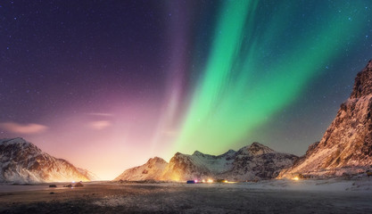Green and purple aurora borealis over snowy mountains. Northern lights in Lofoten islands, Norway....