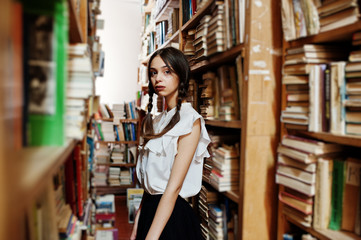 Fototapeta premium Girl with pigtails in white blouse at old library.