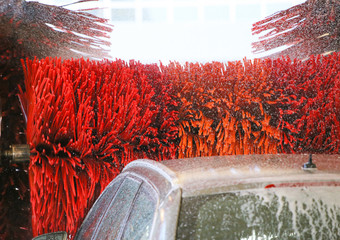 Car wash automatic, red rotating brushes, water spray. Water drops on glass