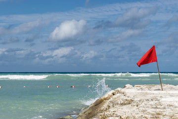 Red Caution Flag on ocean rock by the beach due to high tides, in Montego Bay, Jamaica