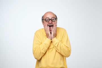 Mature man in funny glasses looking at camera with scared emotion on face.