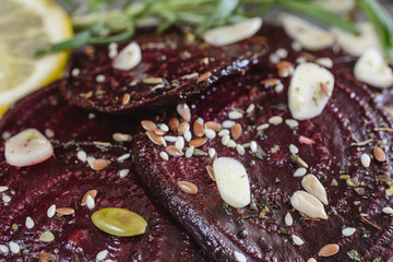 Obraz na płótnie Canvas Baked beetroot sliced in slices with spice and slices of garlic next to a branch of rosemary 