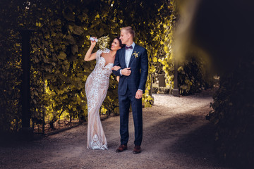 Fototapeta premium Happy wedding couple is walking by a beautiful garden.