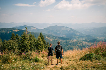 Fototapeta na wymiar A guy and a girl hug each other on top of a mountain. Tourists enjoy the view of the Carpathian Mountains, Ukraine. Instagram filter.