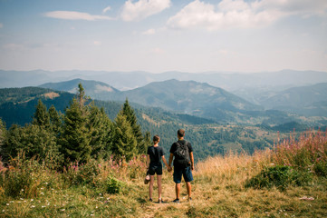 Obraz premium A guy and a girl hug each other on top of a mountain. Tourists enjoy the view of the Carpathian Mountains, Ukraine. Instagram filter.
