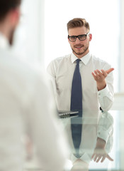 Manager talks to the employee sitting at his Desk